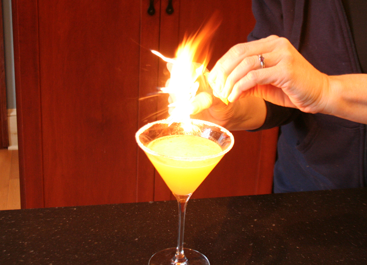 Flaming the Orange Peel over a Tangerine Drop Martini